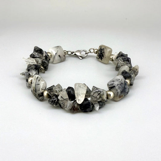 Rutilated quartz bracelet, 19cm, irregular nugget beads in grey, black, and white tones with metal spacers and clasp.