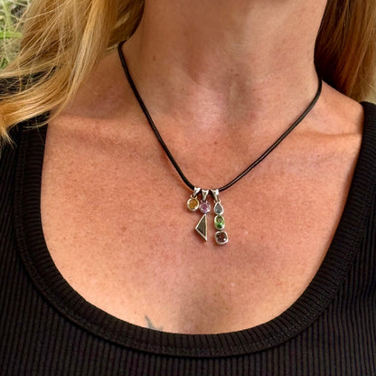 Handcrafted three-pendant gemstone necklace with sapphires, ruby, spinel, and tsavorite (5.81 ct total) on a black leather cord — modular design in white-gold-plated silver.