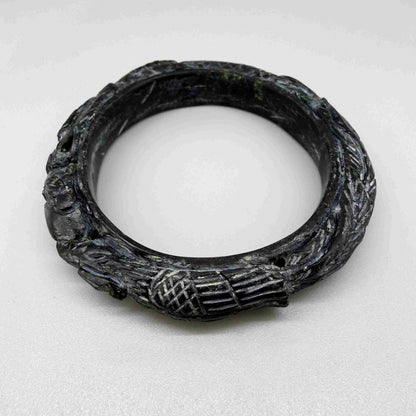Carved dark jade-style bangle with sculptural relief details and polished surface, 19 cm inner circumference