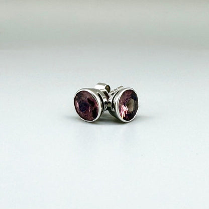 White gold stud earrings featuring round-cut rhodolite garnets in a classic setting.