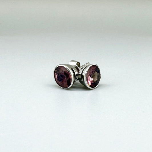 White gold stud earrings featuring round-cut rhodolite garnets in a classic setting.