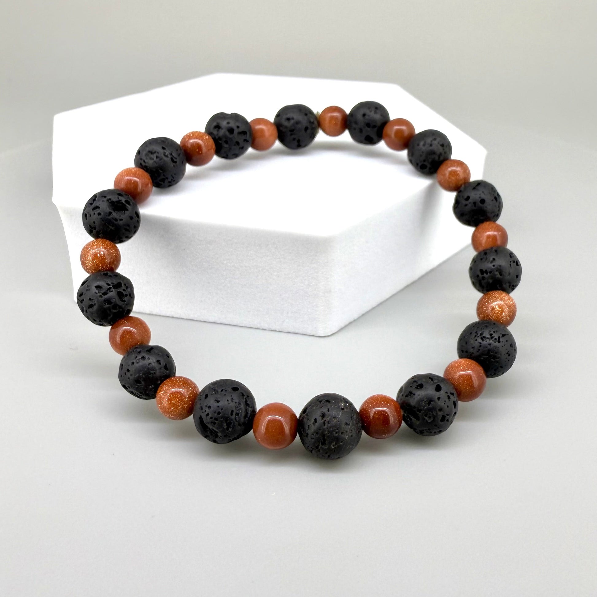 Lava and goldstone beaded bracelet, 18cm, alternating matte black lava beads and smaller shimmering golden-brown man-made goldstone beads on elastic stretch band.