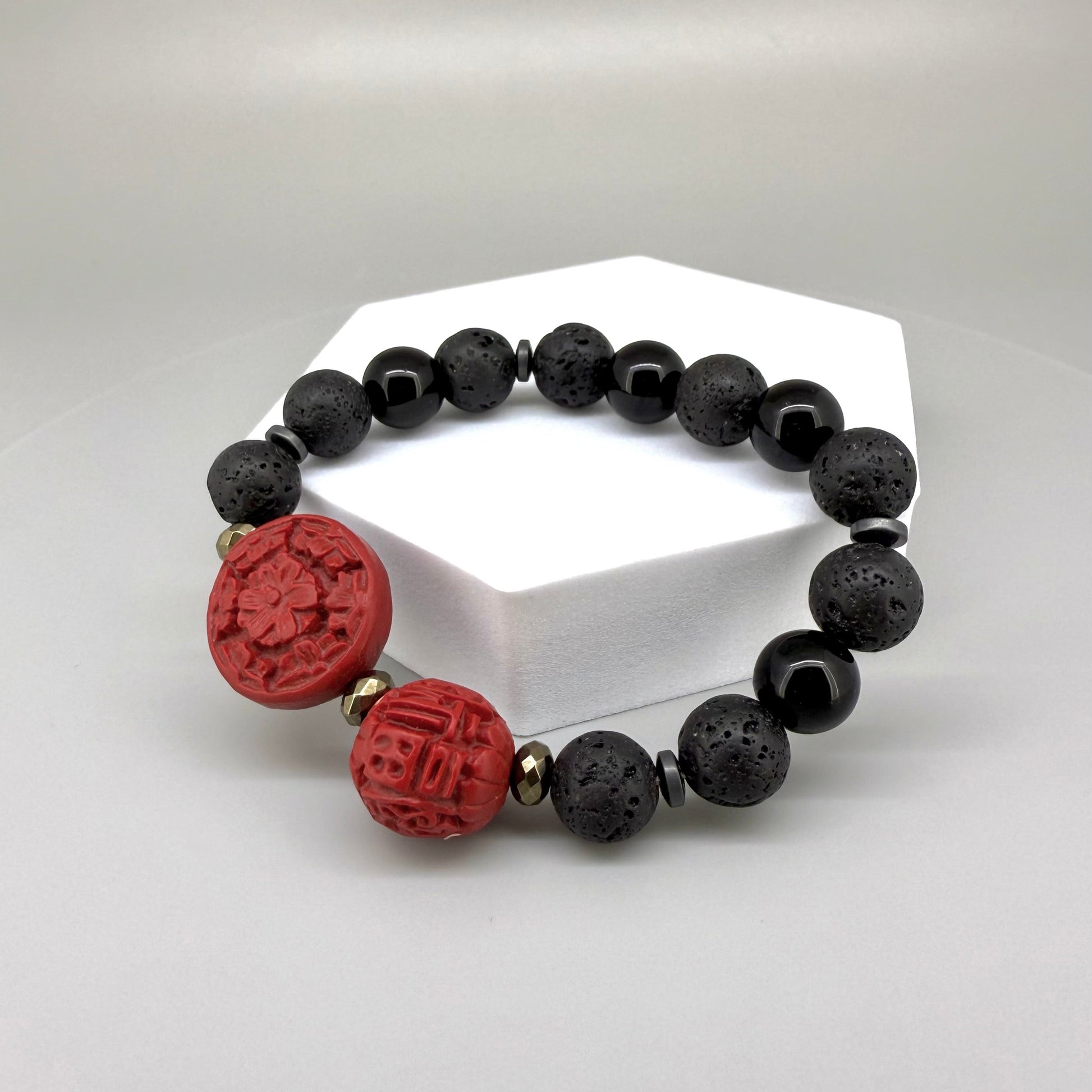 Lava and cinnabar-style beaded bracelet, 18cm, black lava beads with two carved red resin accent beads on elastic stretch band.