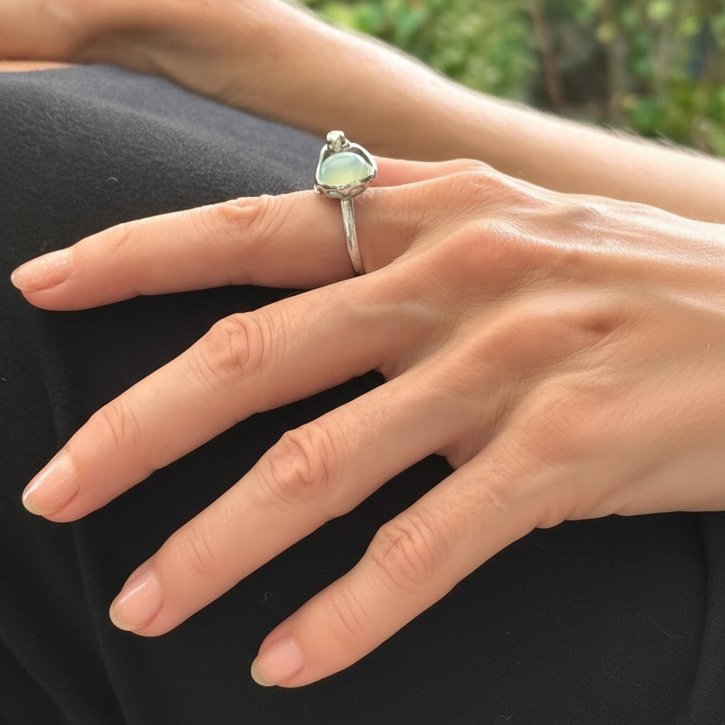 Handcrafted sterling silver ring with bird motif, featuring a 4.76 ct chalcedony cabochon resembling water in a fountain.
