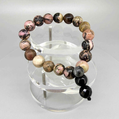 Rhodonite mala bracelet with natural pink gemstone beads and dark veining, featuring decorative charm detail.