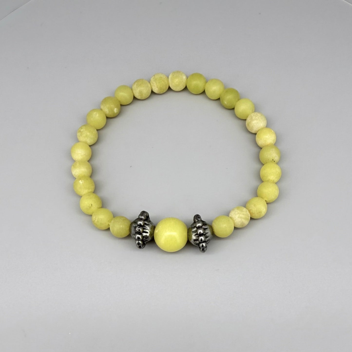 Yellow jasper beaded bracelet, 18cm, vibrant gemstone beads with larger focal bead framed by carved metal accents on elastic stretch band.