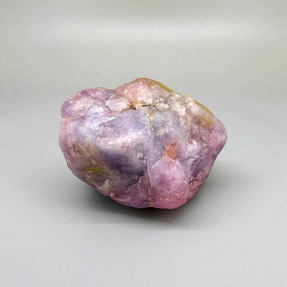 Natural ruby rough stone in lilac to purplish-pink tones, uncut corundum specimen.