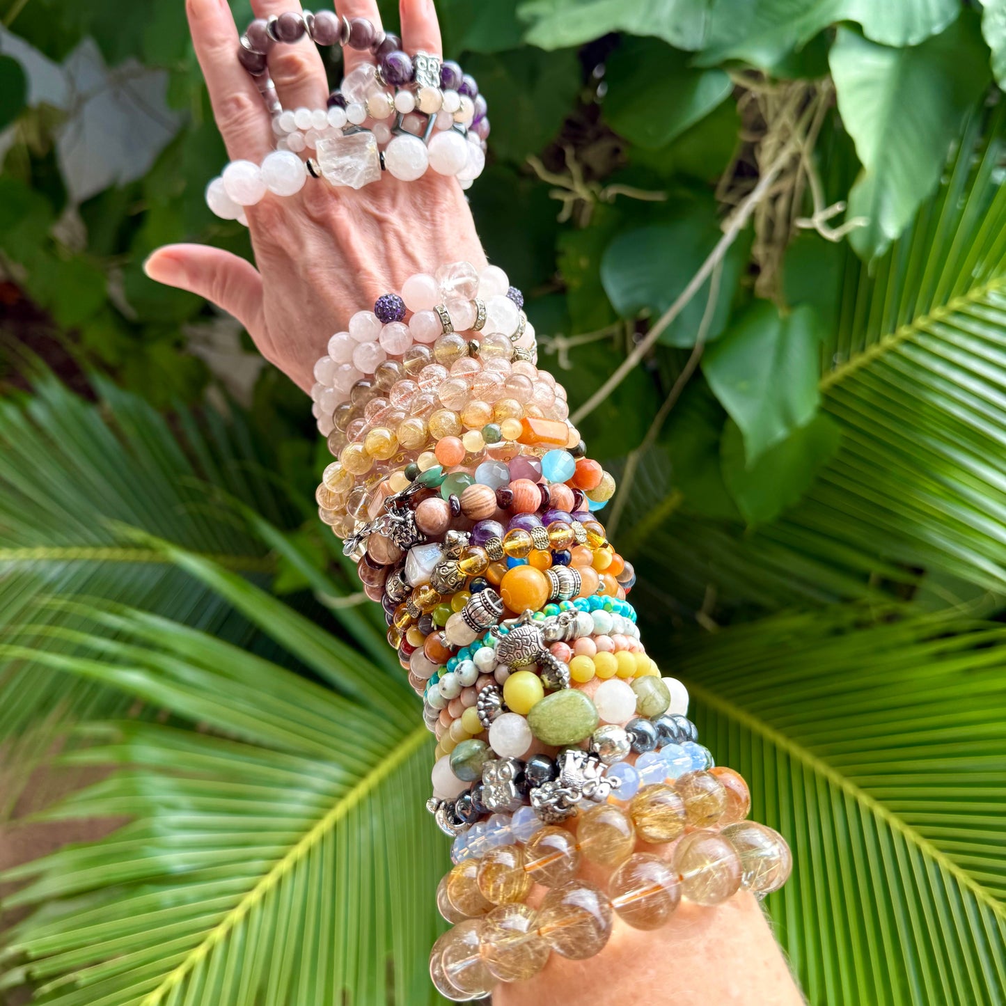 Multiple natural gemstone bracelets worn on arm and hand