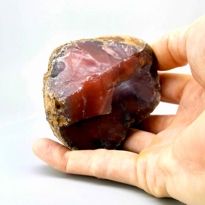 Natural red chalcedony rough (quartz) with warm orange to deep red tones, uncut gemstone.