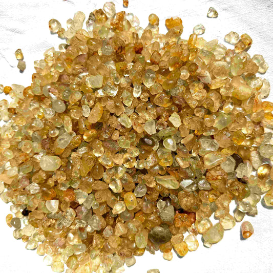 Natural champagne-gold topaz rough with warm golden tones, uncut and untreated, photographed on neutral background.