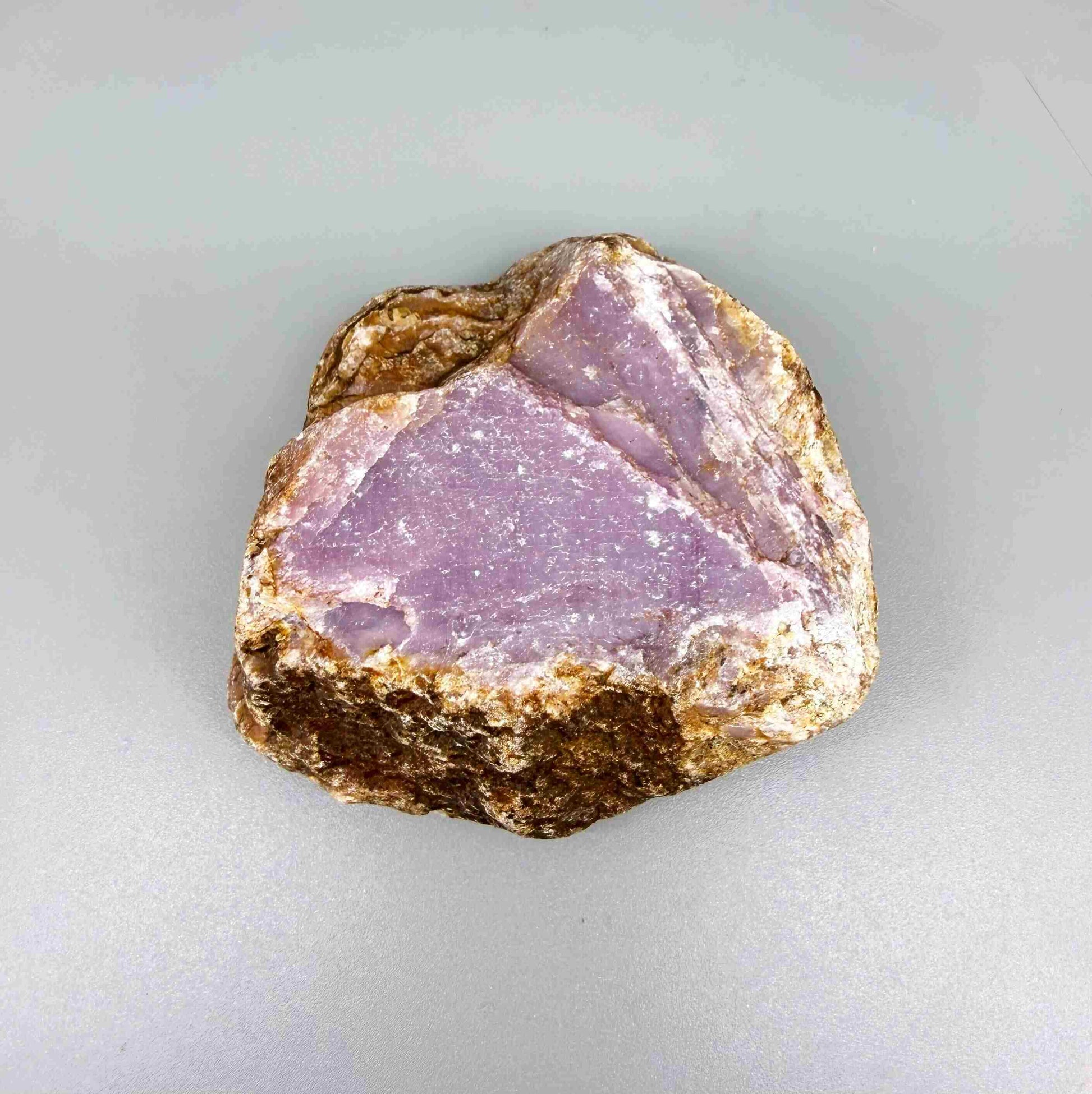 Natural ruby rough stone with purple-pink tones in host rock, uncut corundum specimen