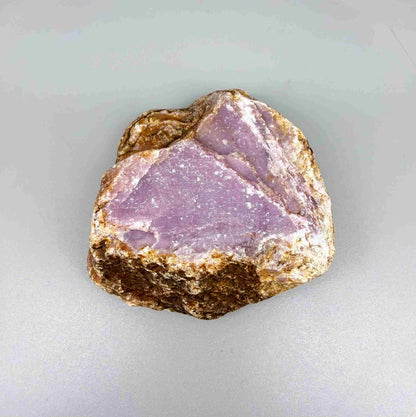 Natural ruby rough stone with purple-pink tones in host rock, uncut corundum specimen