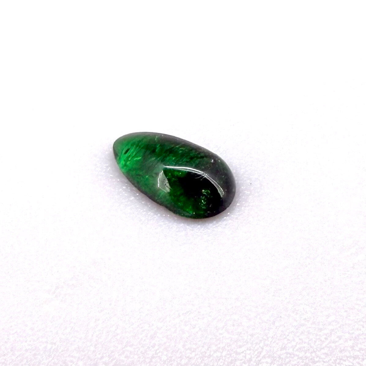 0.67 ct natural untreated emerald from Zambia, one side polished and the other cabochon-shaped.
