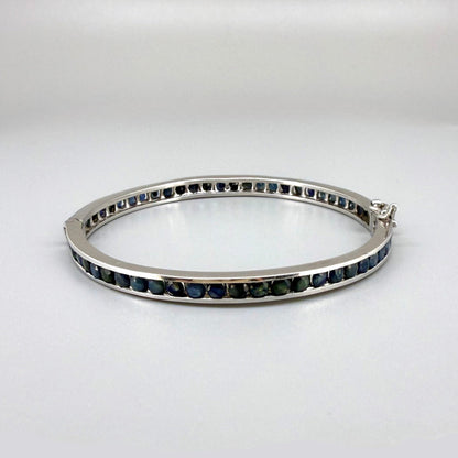 Blue sapphire bangle in sterling silver with white gold plating on neutral background