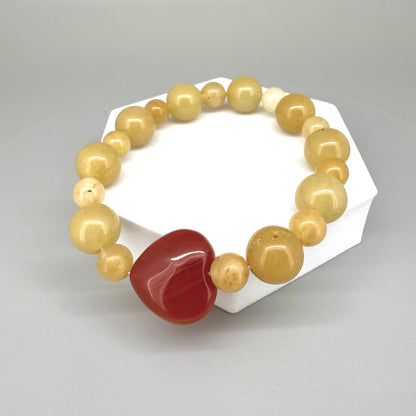 Jade and carnelian beaded bracelet, 20cm, yellow-cream jade beads with large heart-shaped orange-red carnelian focal stone on elastic stretch band.