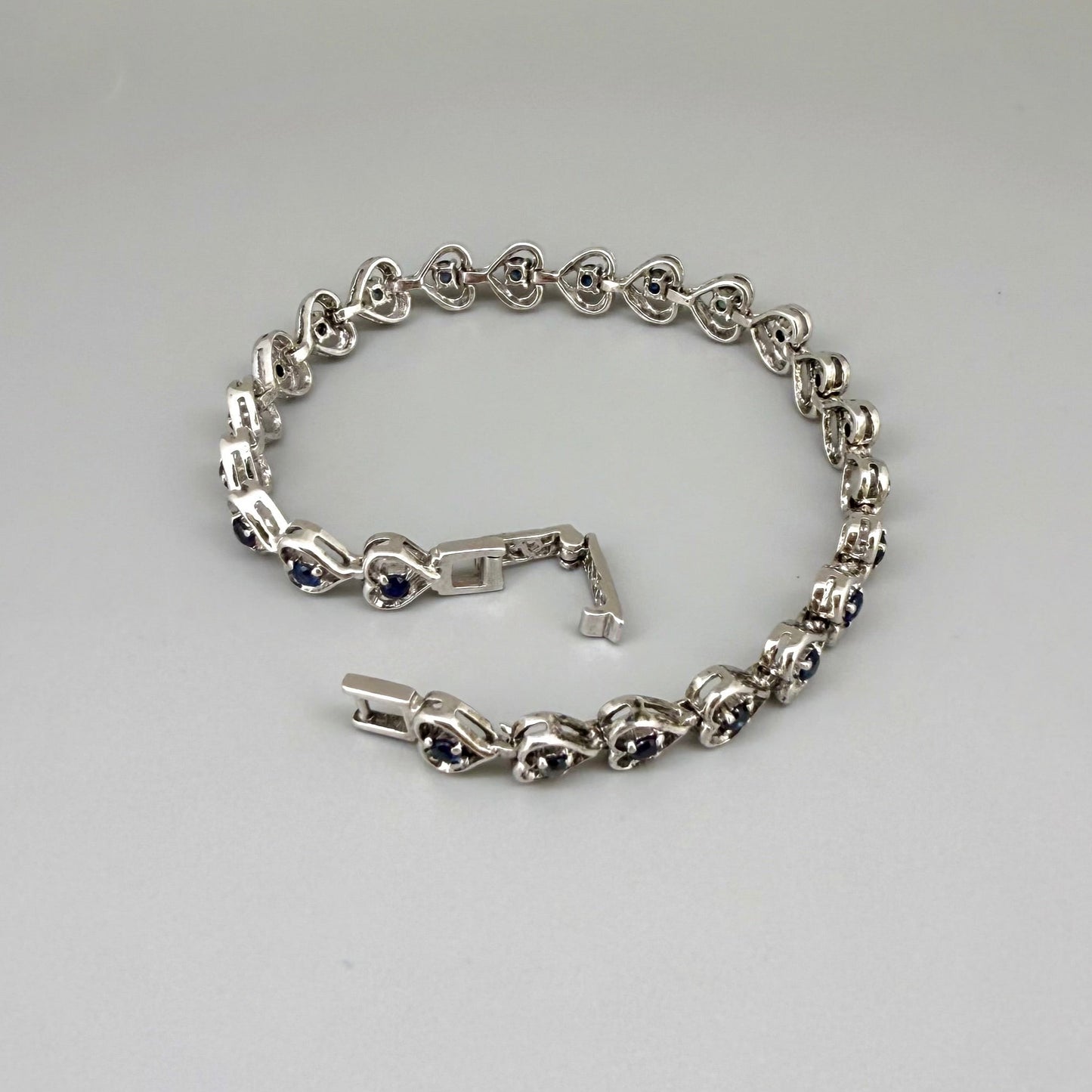 Sapphire bracelet in sterling silver with white gold plating, elegant design on neutral background