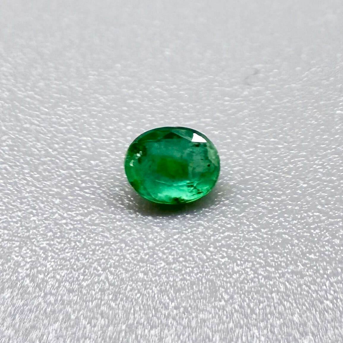 0.2 ct natural untreated Zambian emerald, oval faceted with vivid bluish-green color.