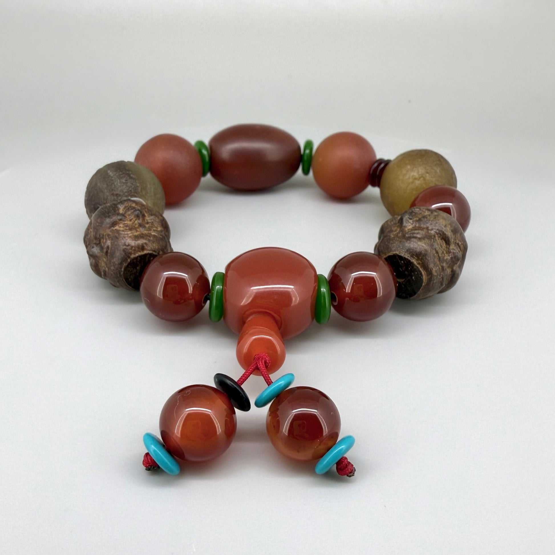 Carnelian and agate beaded bracelet, 20cm, orange-red and brown gemstone beads with two carved wooden head accents on elastic stretch band.
