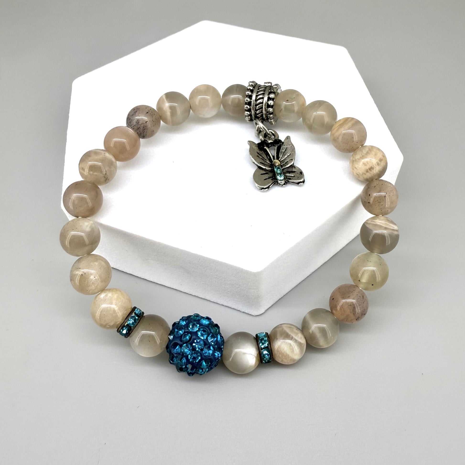Moonstone beaded bracelet, 19cm, beige earthy gemstone beads with blue decorative bead and silver butterfly charm on elastic stretch band.