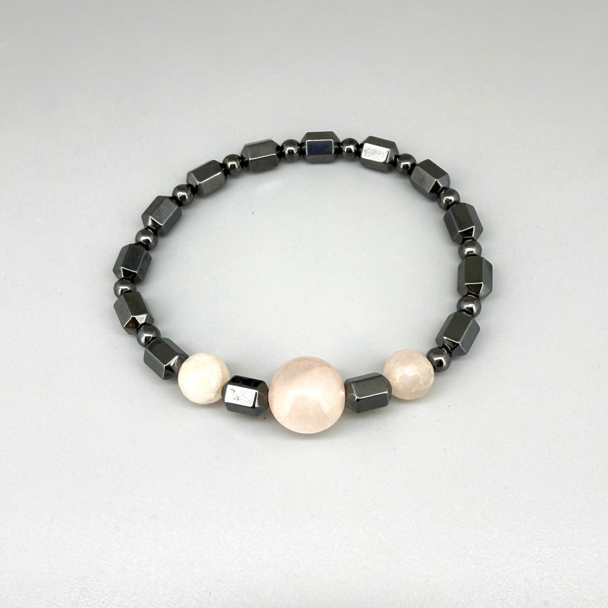 Hematite and rose quartz beaded bracelet, 18cm, geometric metallic grey beads with three pink rose quartz accents on elastic stretch band.