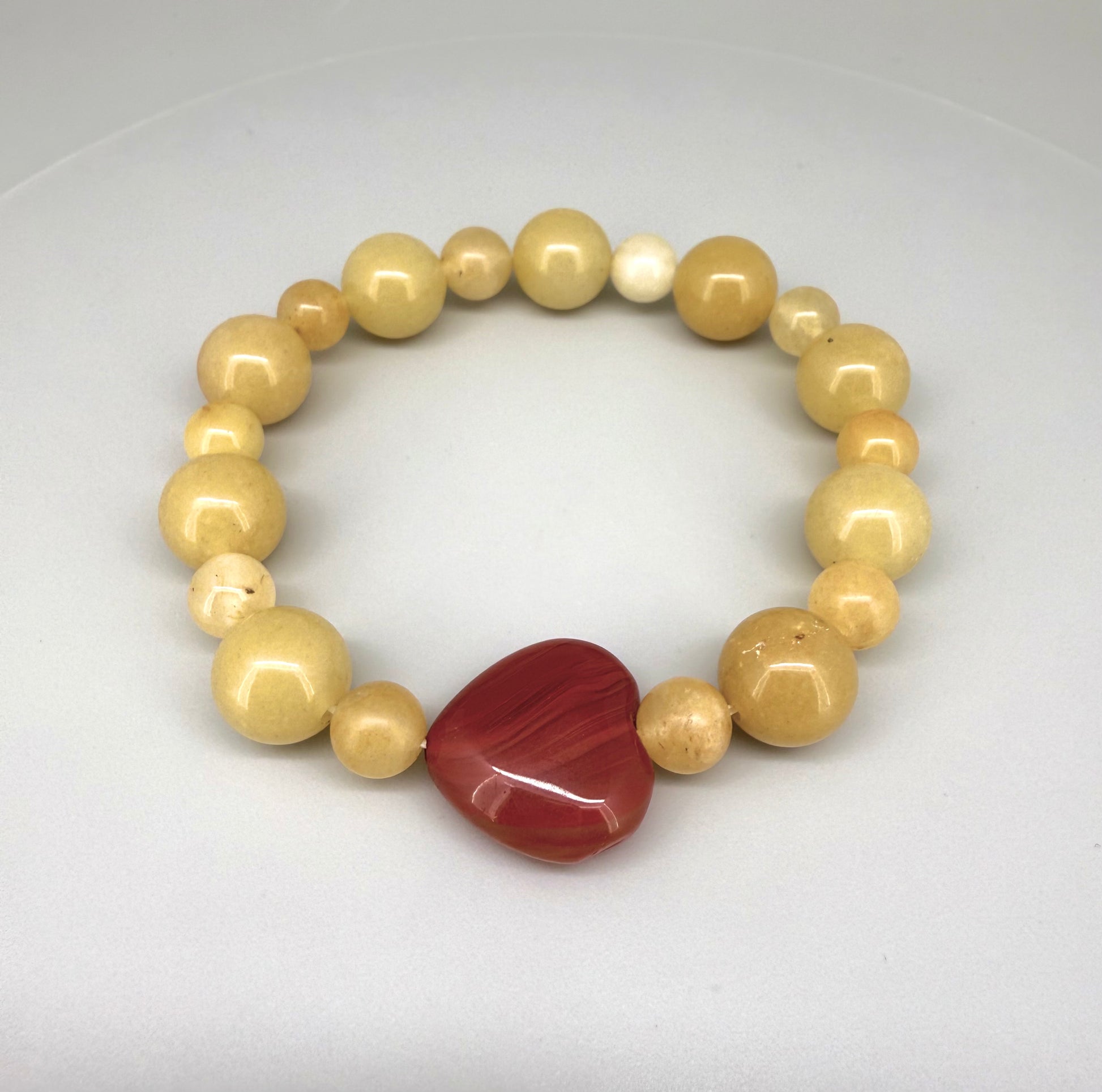 Jade and carnelian beaded bracelet, 20cm, yellow-cream jade beads with large heart-shaped orange-red carnelian focal stone on elastic stretch band.