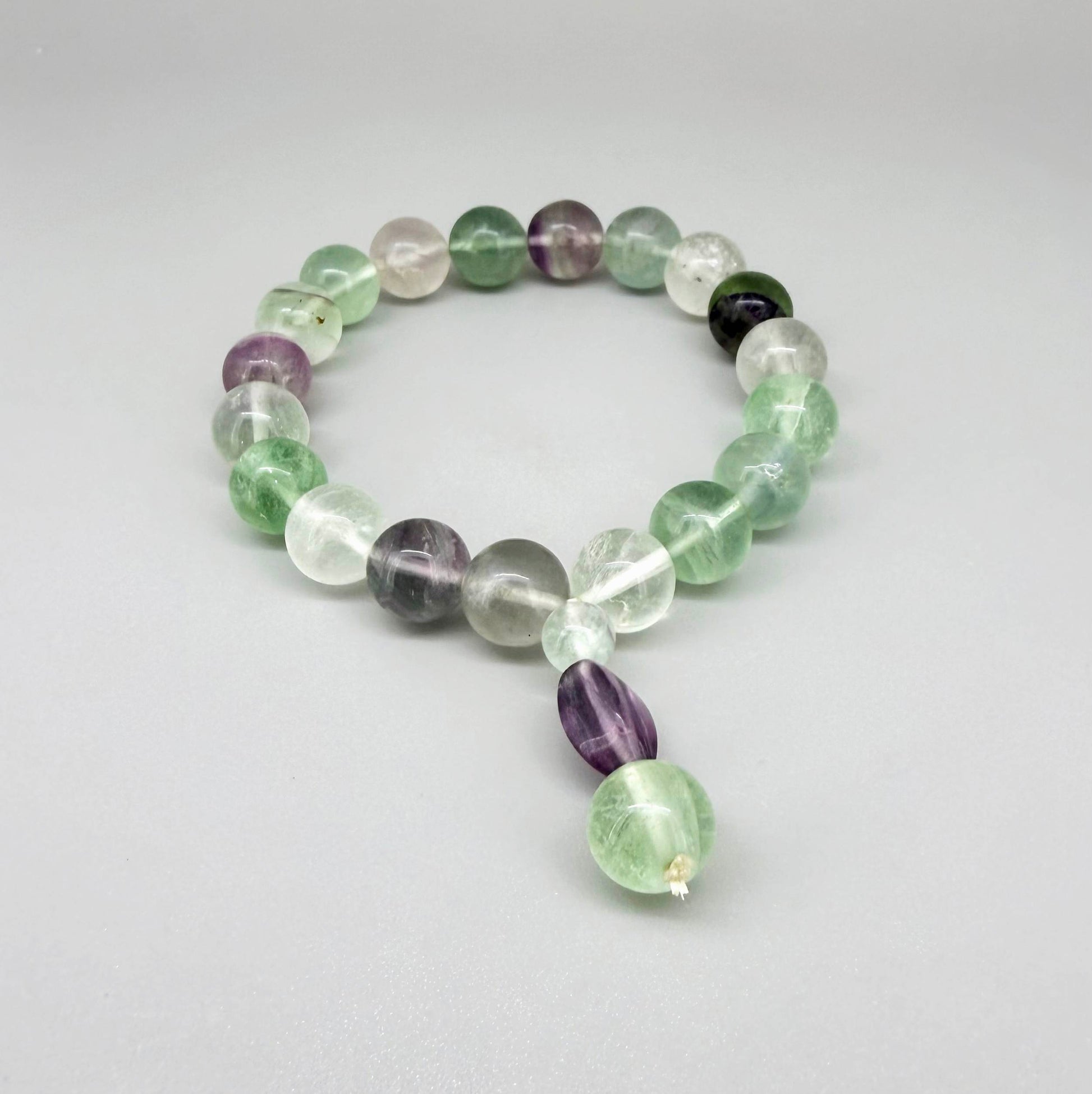 Fluorite mala bracelet with green and purple translucent gemstone beads and decorative charm detail.