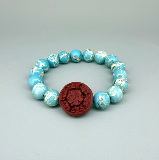 Varescite beaded bracelet, 18cm, turquoise-green gemstone beads with carved red cinnabar-style accent bead on elastic stretch band.