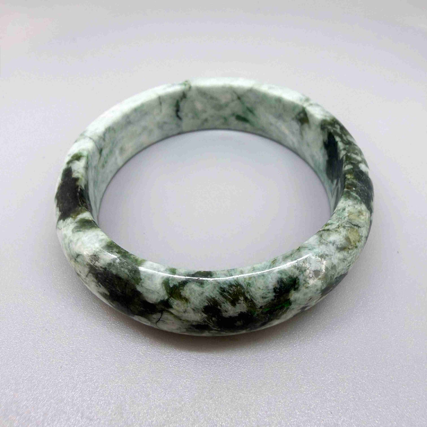 Polished jade bangle in soft green hues with smooth surface and natural variations, 20 cm inner circumference
