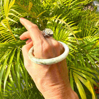 Polished jade bangle in soft green hues with smooth surface and natural variations