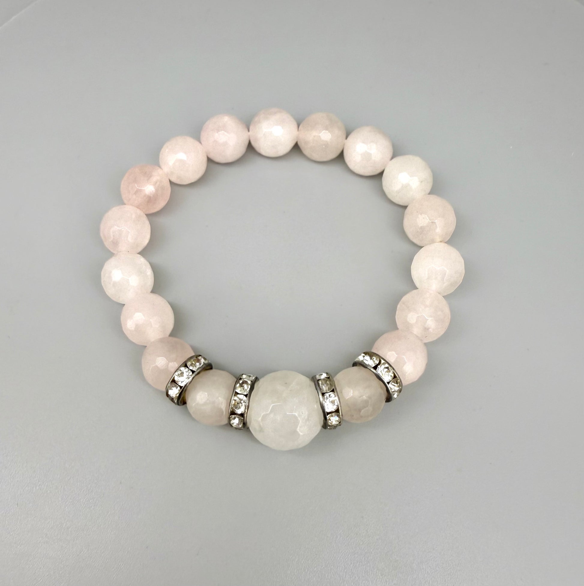 Rose quartz beaded bracelet, 18cm, light pink gemstone beads with larger central bead and decorative metal accents on elastic stretch band.