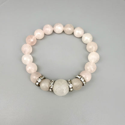 Rose quartz beaded bracelet, 18cm, light pink gemstone beads with larger central bead and decorative metal accents on elastic stretch band.