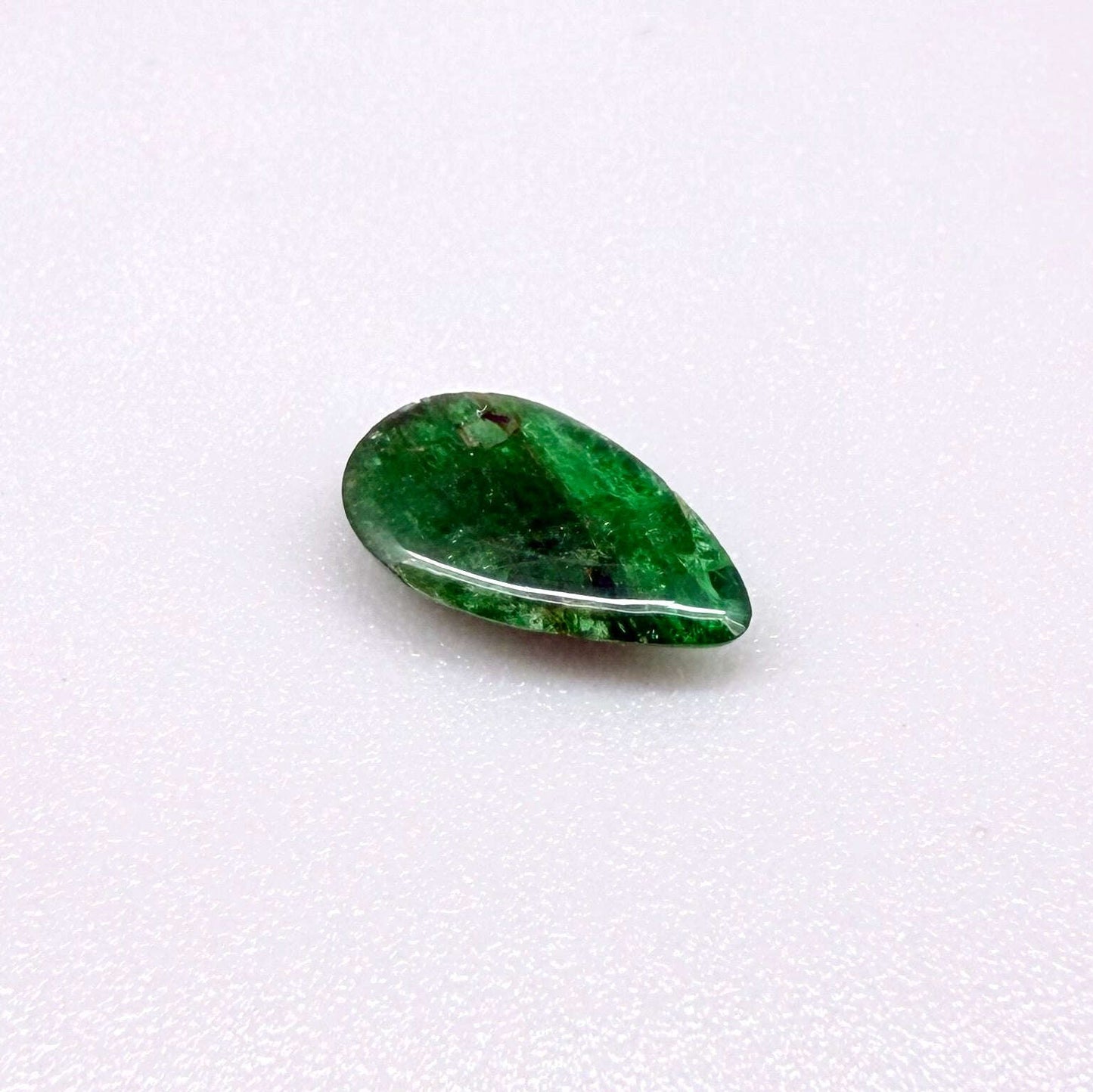 0.9 ct natural untreated emerald from Zambia, one side polished and the other cabochon-shaped.