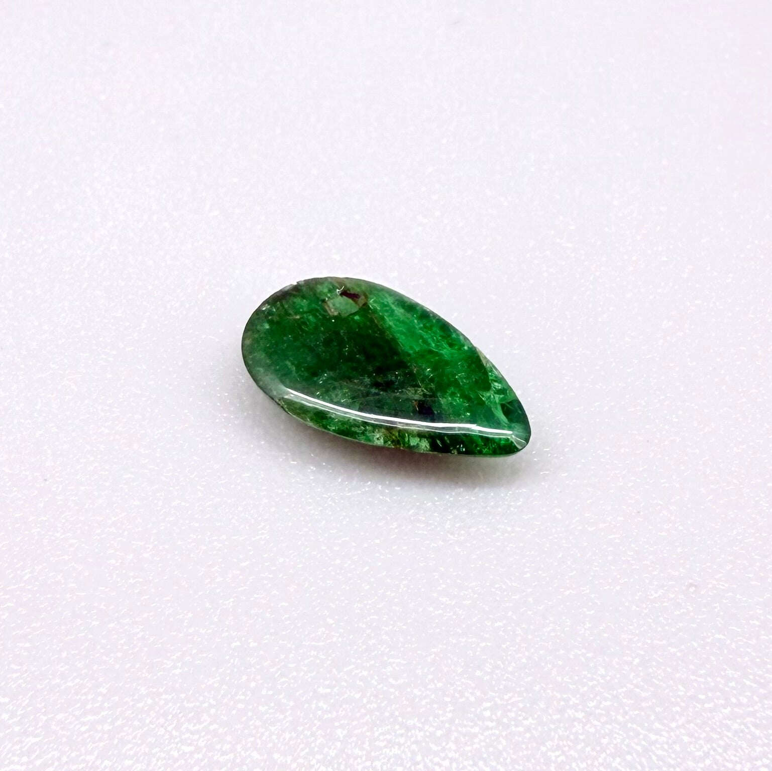 0.9 ct natural untreated emerald from Zambia, one side polished and the other cabochon-shaped.