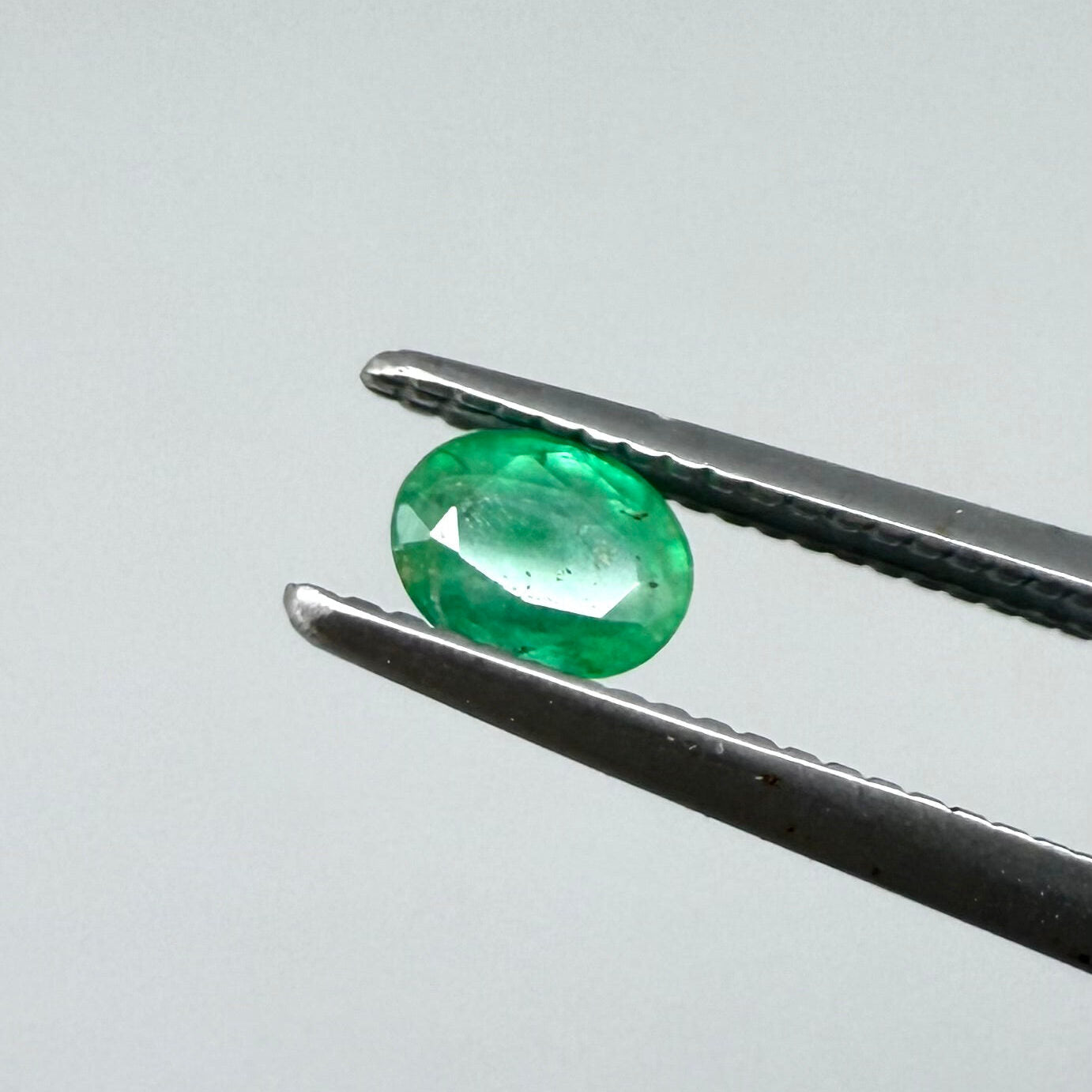 0.2 ct natural untreated Zambian emerald, oval faceted with vivid bluish-green color.