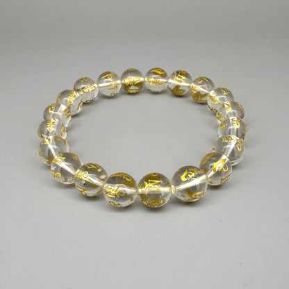 Clear quartz beaded bracelet, 19cm, transparent gemstone beads engraved with golden Sanskrit mantra Om Mani Padme Hum on elastic stretch band.