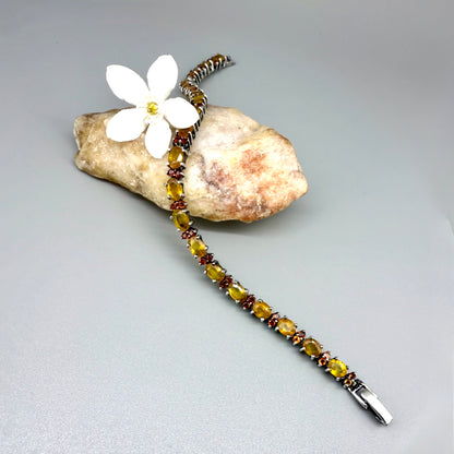 White gold plated sapphire bracelet in yellow, orange, and red hues on neutral background