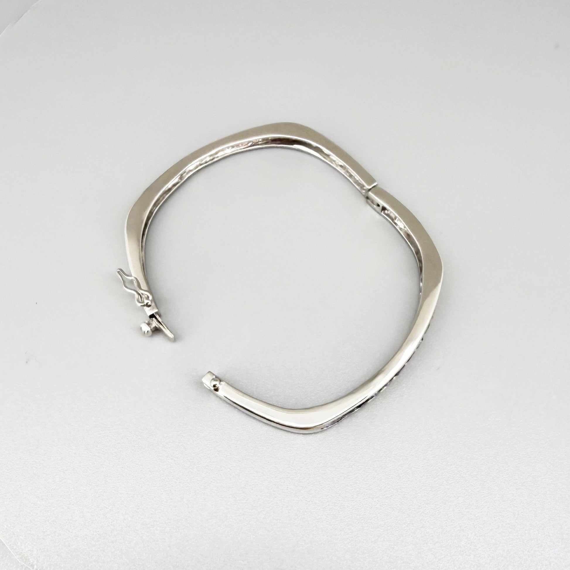 White gold plated sterling silver bangle with faceted natural iolite gemstones in violet-blue tones.