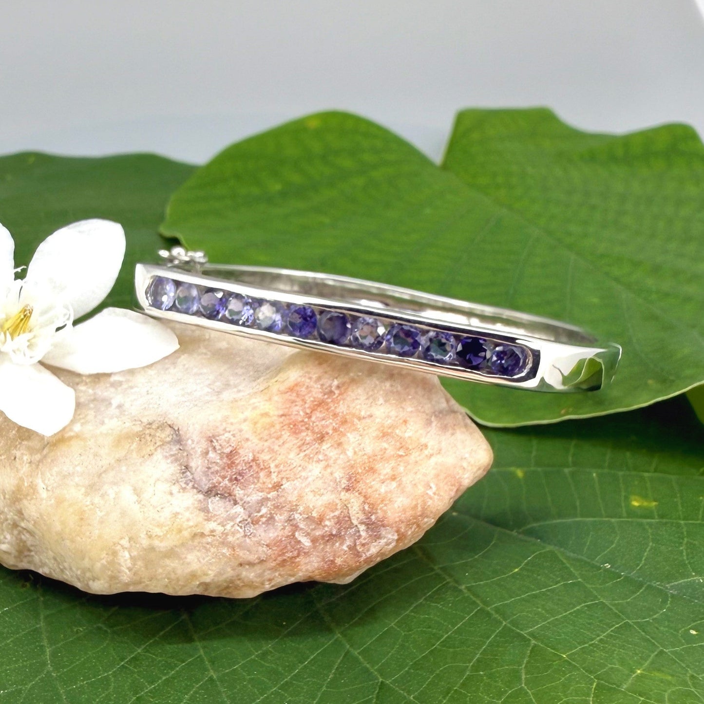 White gold plated sterling silver bangle with faceted natural iolite gemstones in violet-blue tones.