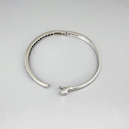 Blue sapphire bangle in white gold plated sterling silver with faceted deep blue gemstones.
