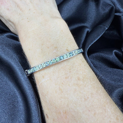 White gold plated silver bangle set with faceted natural green sapphires.