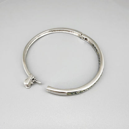 White gold plated silver bangle set with faceted natural green sapphires.