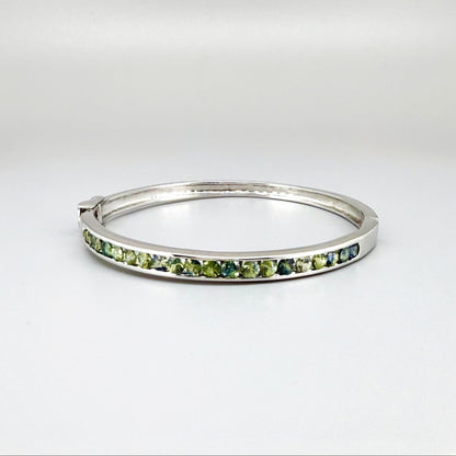 White gold plated silver bangle set with faceted natural green sapphires.