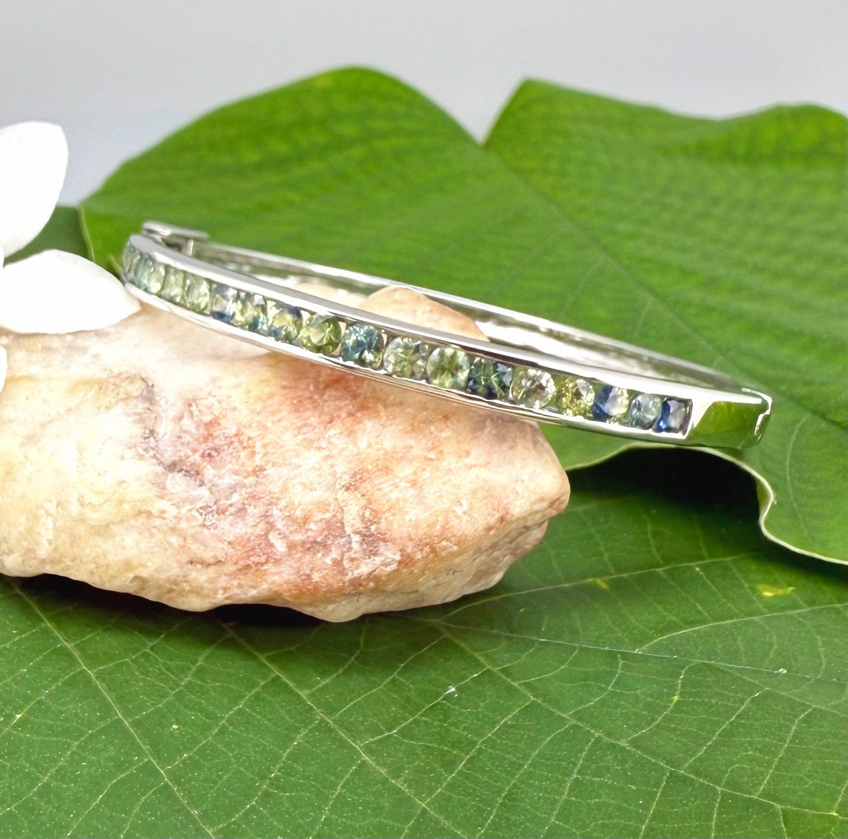 White gold plated silver bangle set with faceted natural green sapphires.