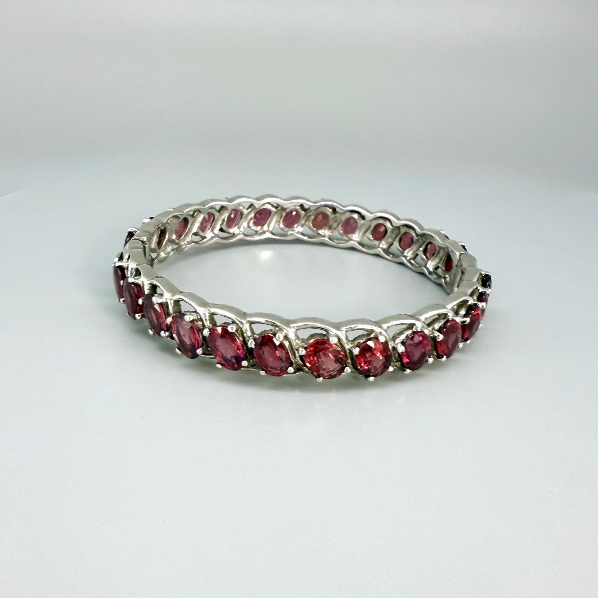 Rhodolite garnet bangle in sterling silver with white gold plating on neutral background