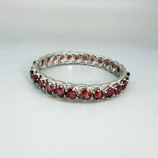 Rhodolite garnet bangle in sterling silver with white gold plating on neutral background
