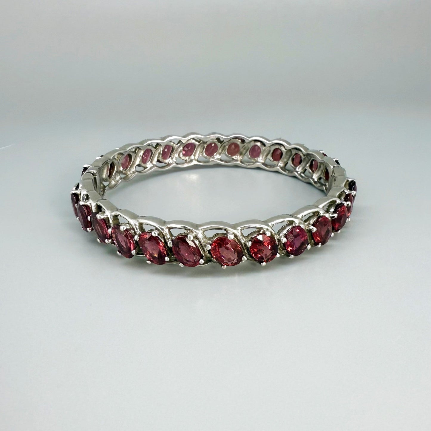 Rhodolite garnet bangle in sterling silver with white gold plating on neutral background