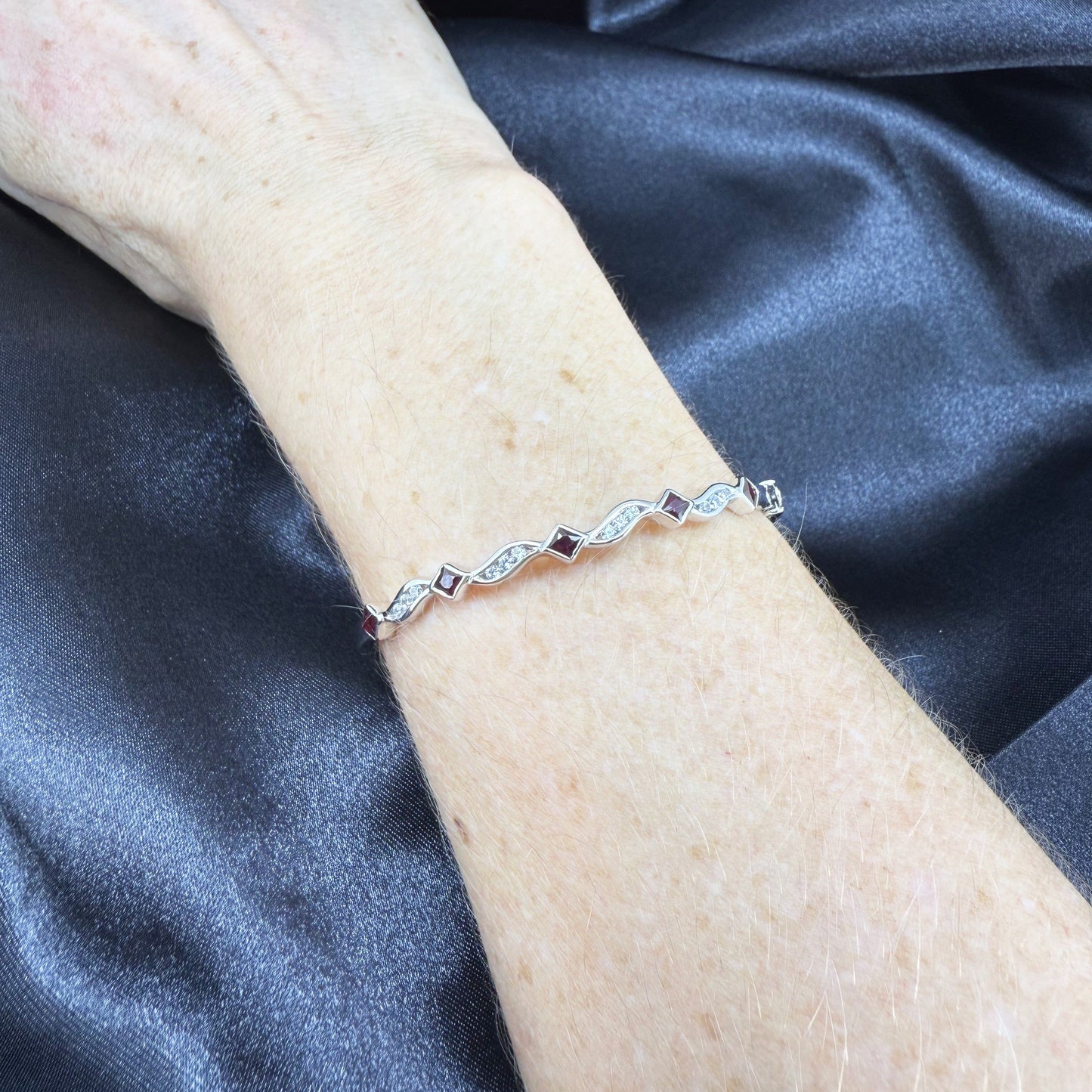 White gold plated silver bangle with natural rubies and cubic zirconia in a refined alternating design.