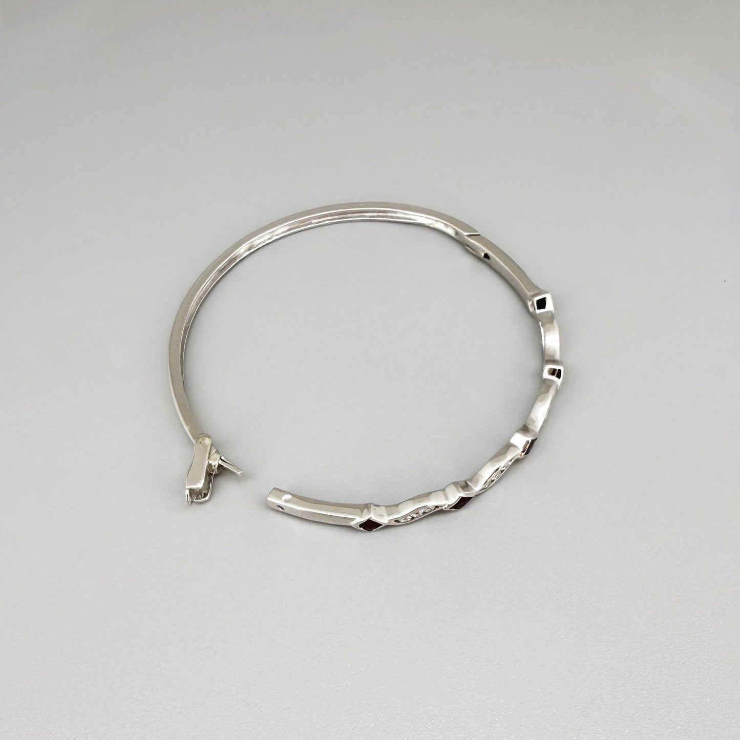 White gold plated silver bangle with natural rubies and cubic zirconia in a refined alternating design.