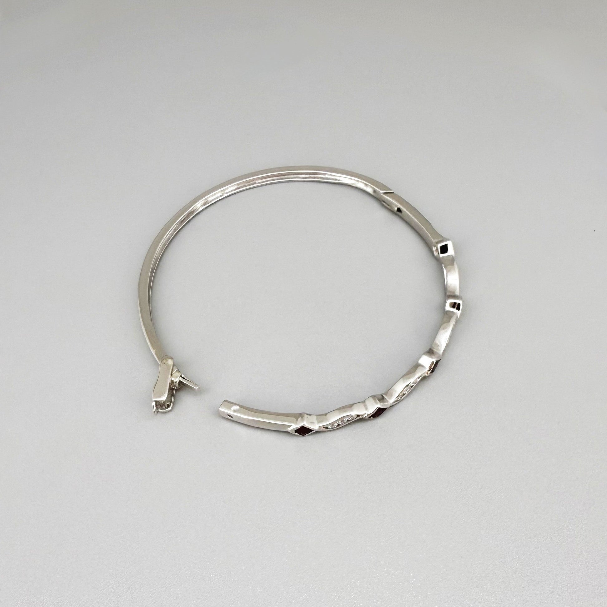 White gold plated silver bangle with natural rubies and cubic zirconia in a refined alternating design.