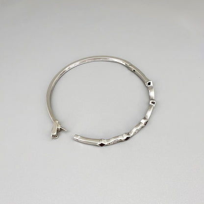 White gold plated silver bangle with natural rubies and cubic zirconia in a refined alternating design.